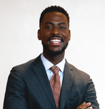 Black male therapist in Chicago smiling and wearing a suit and tie.
