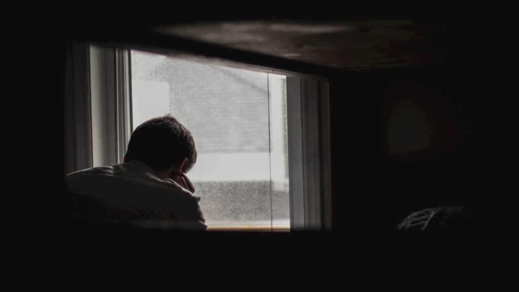 moody male sitting by window
