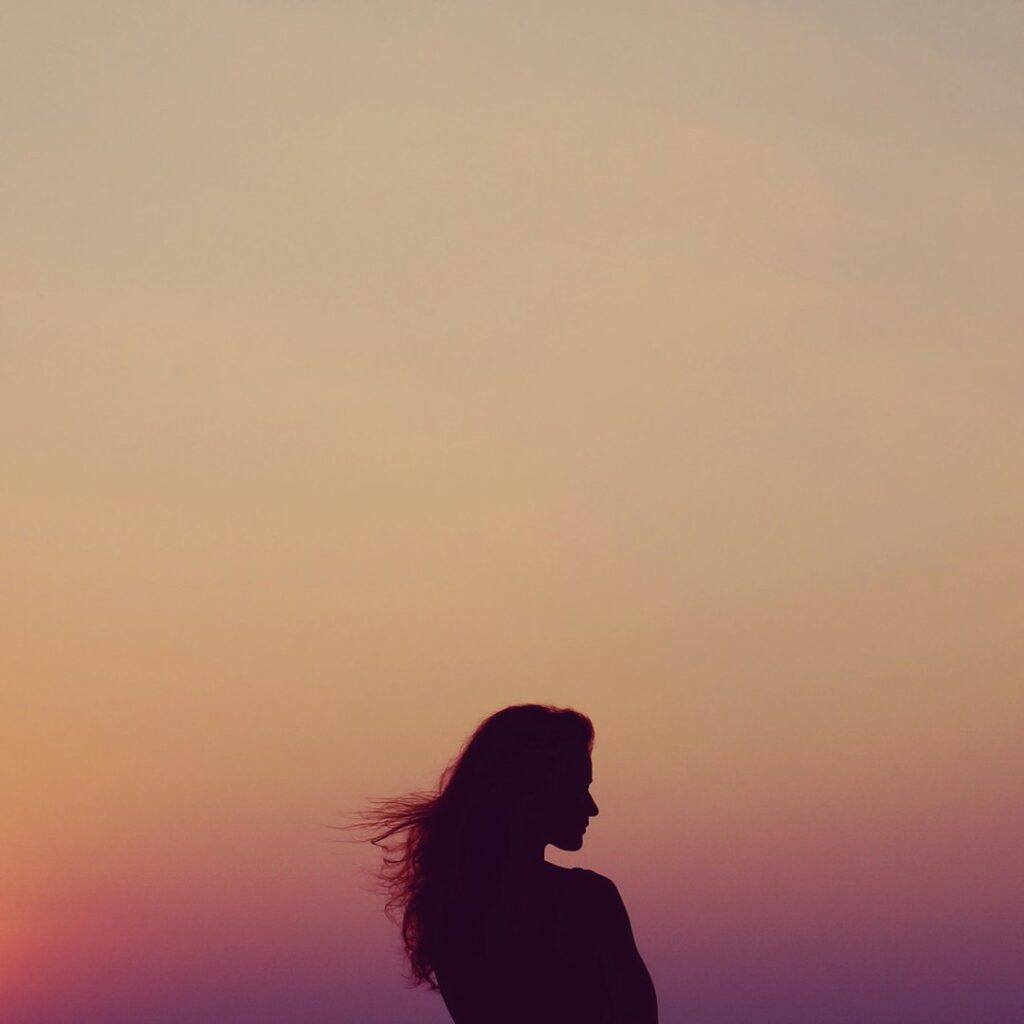 shadowy woman silhouette sunset with yellow and pink sky.
