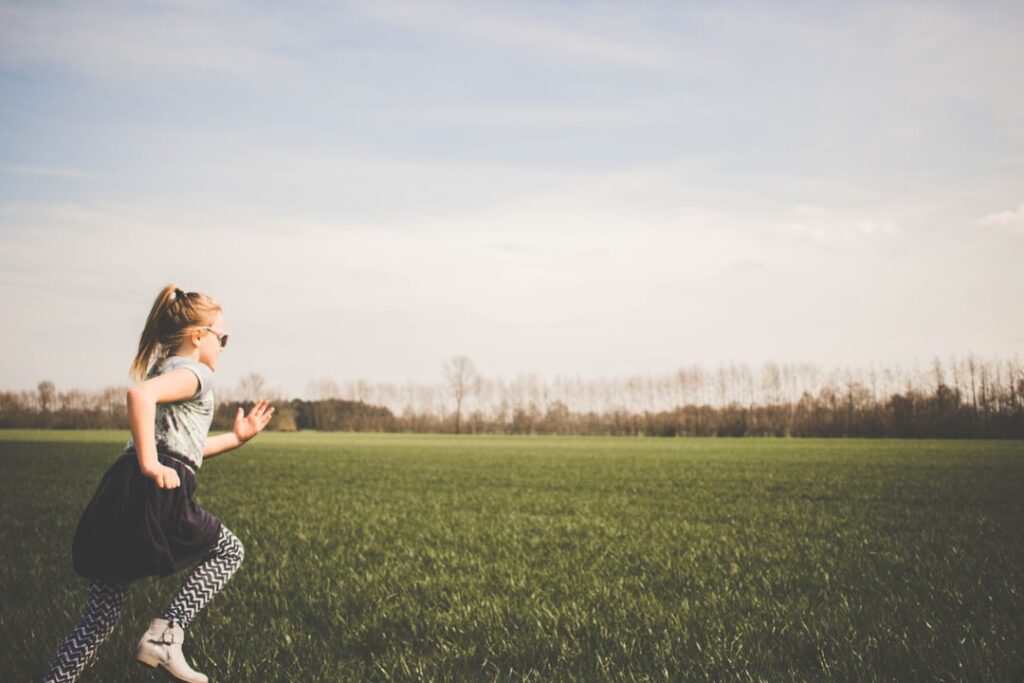 girl with adhd running through a grass field