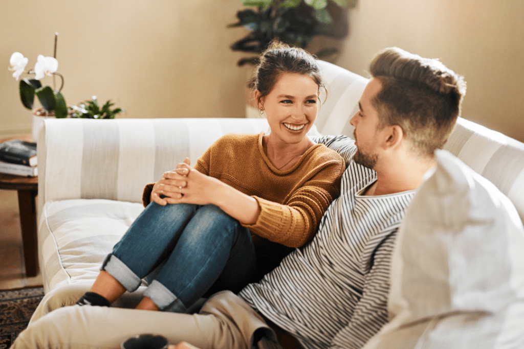 Couple cuddling on a gray and white striped couch, while discussing their relationship blueprint prior to attending premarital counseling.