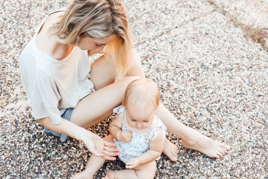 tired white mother sitting on ground with baby girl