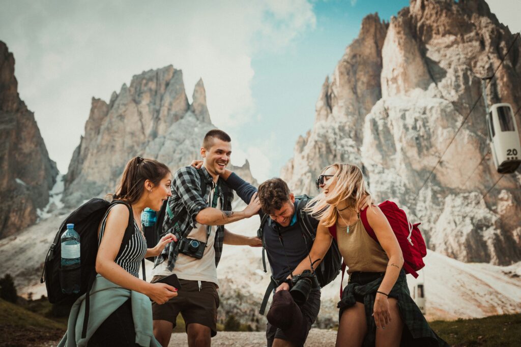 Four friends laughing on hiking trip at base of mountains