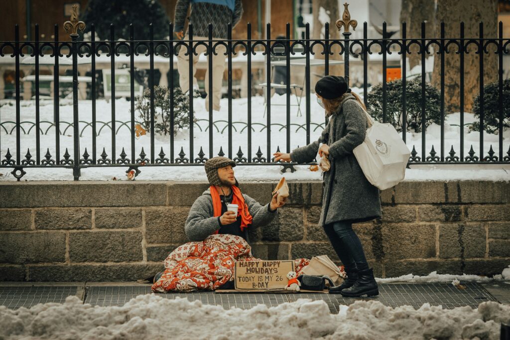 Woman giving to a homeless man on the street in the winter