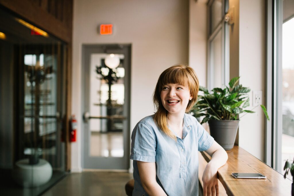 A young woman smiling in a peaceful therapy office, representing relief & confidence after panic attack treatment in Chicago.