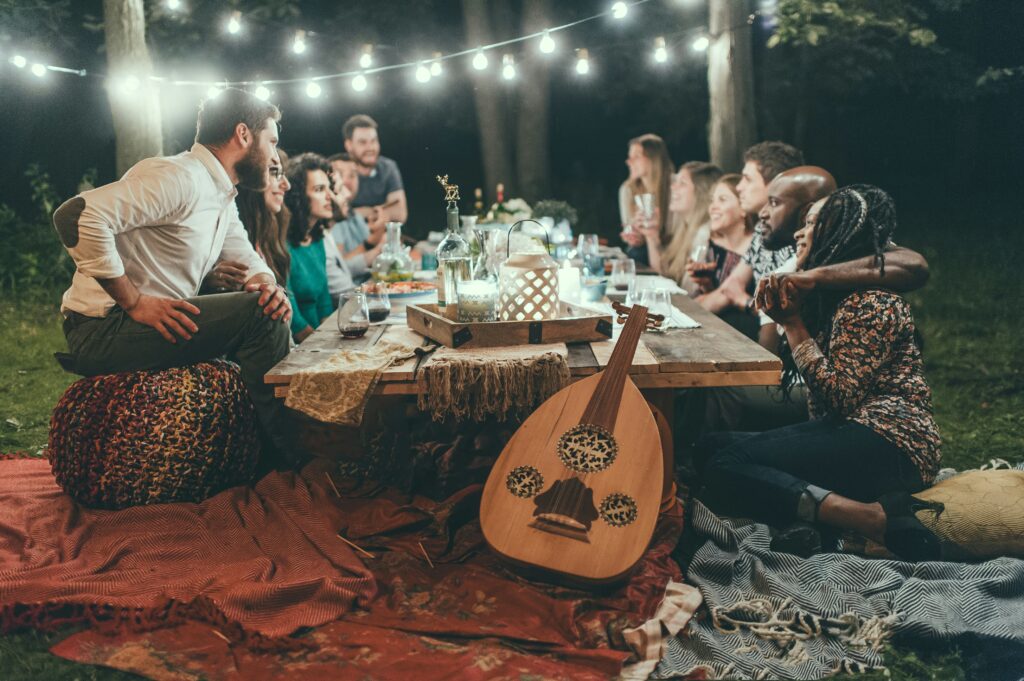 Friends enjoying a feast under string lights, representing the celebration and joy found in chosen family bonds