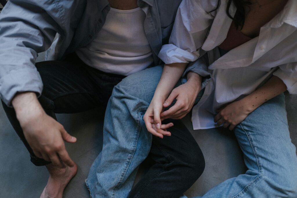 A couple wearing denim sitting close to each other practicing sensate focus touch. 