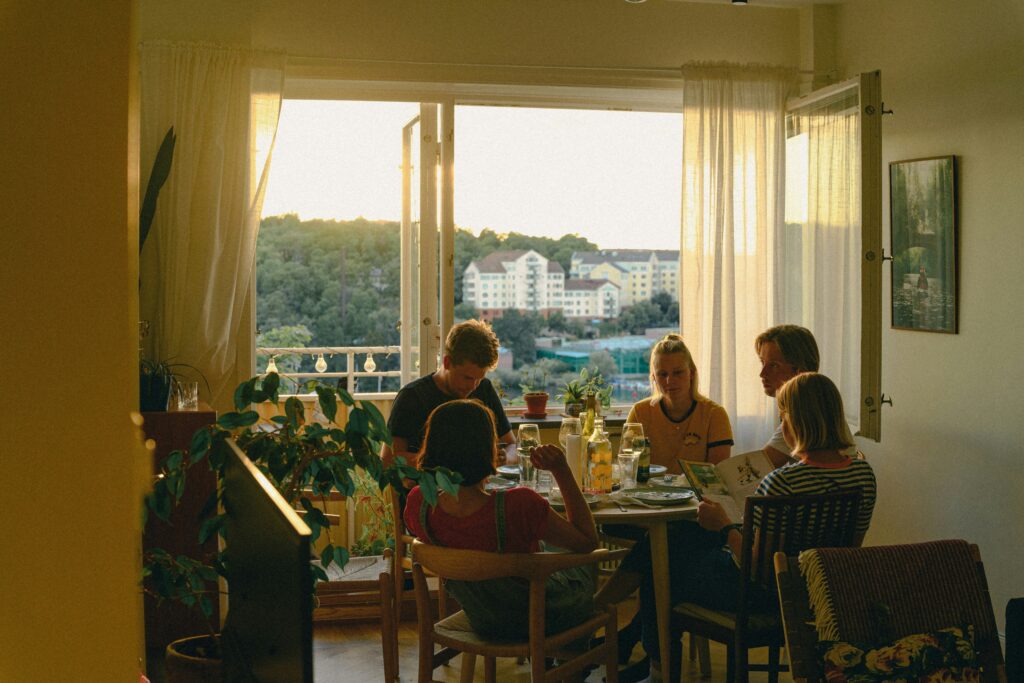 Friends sharing a meal in a sunlit apartment, demonstrating the intimate spaces people connect