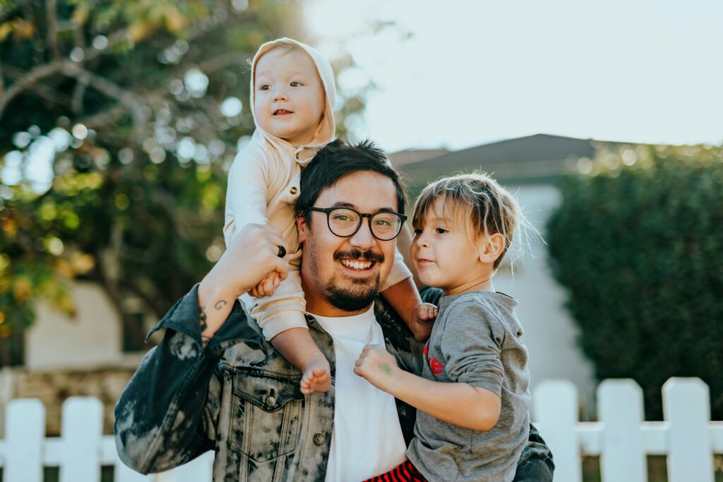 A smiling father holding his two young children, representing love, connection, and the importance of strong family bonds.