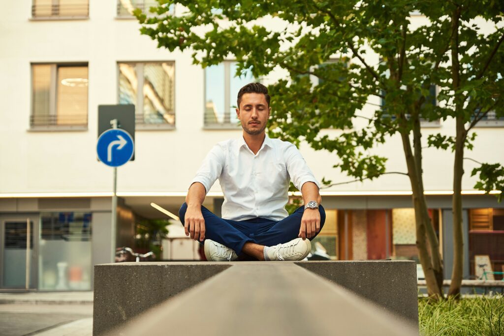 Businessman practicing mindfulness meditation outdoors, demonstrating an effective coping skill for managing anxiety in everyday environments.