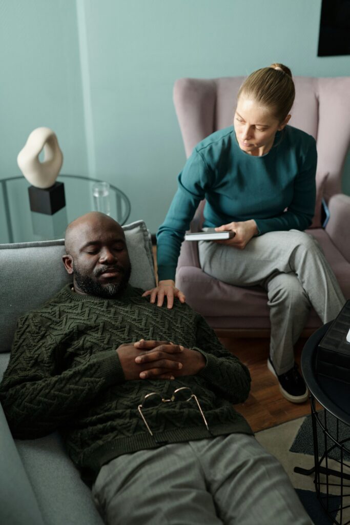 Therapist attentively taking notes while client relaxes in a calming therapy space, creating a supportive environment for anxiety treatment goal discussions.