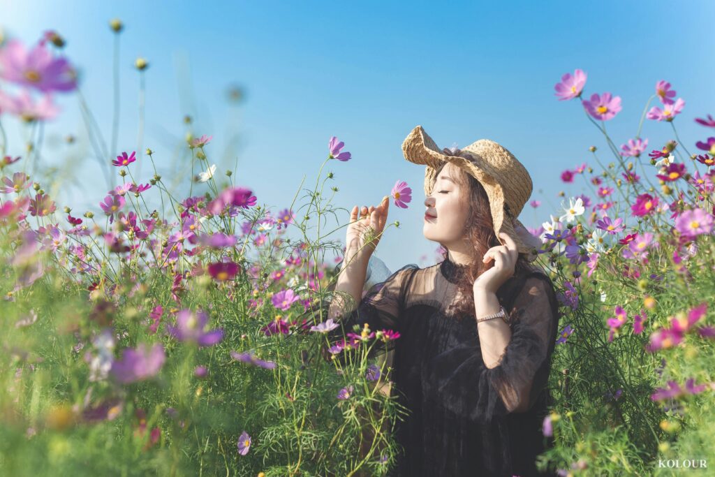 Finding peace and renewal—A woman stands in a sunlit field of flowers, breathing deeply and embracing the beauty around her.