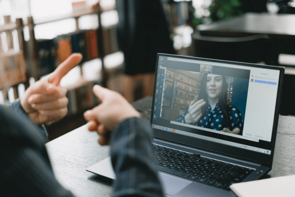 Man wearing black dress shirt on a video call therapy session on a laptop, with woman therapist wearing blue and white polka dot shirt.