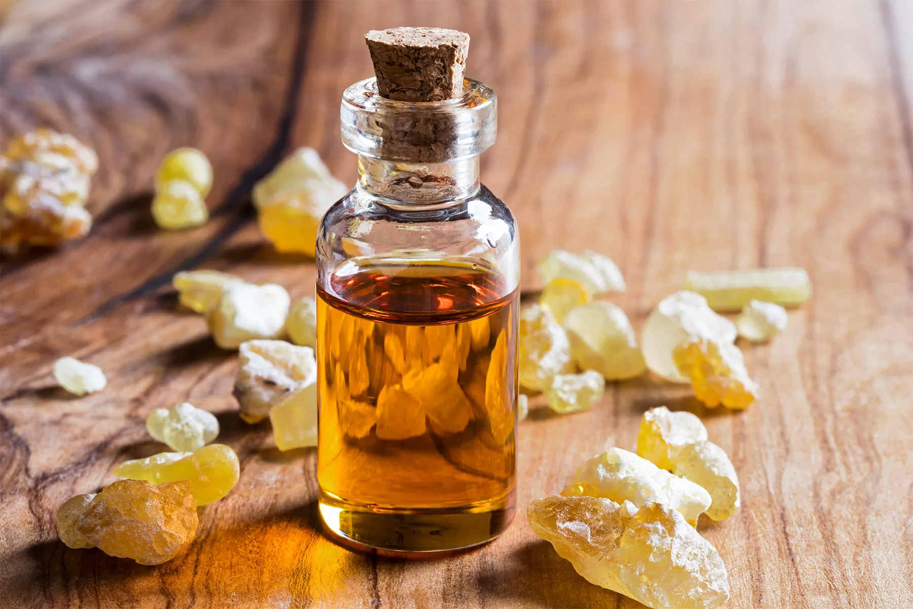 Frankincense essential oil for OCD relief, glass bottle with golden resin drops on a wooden table