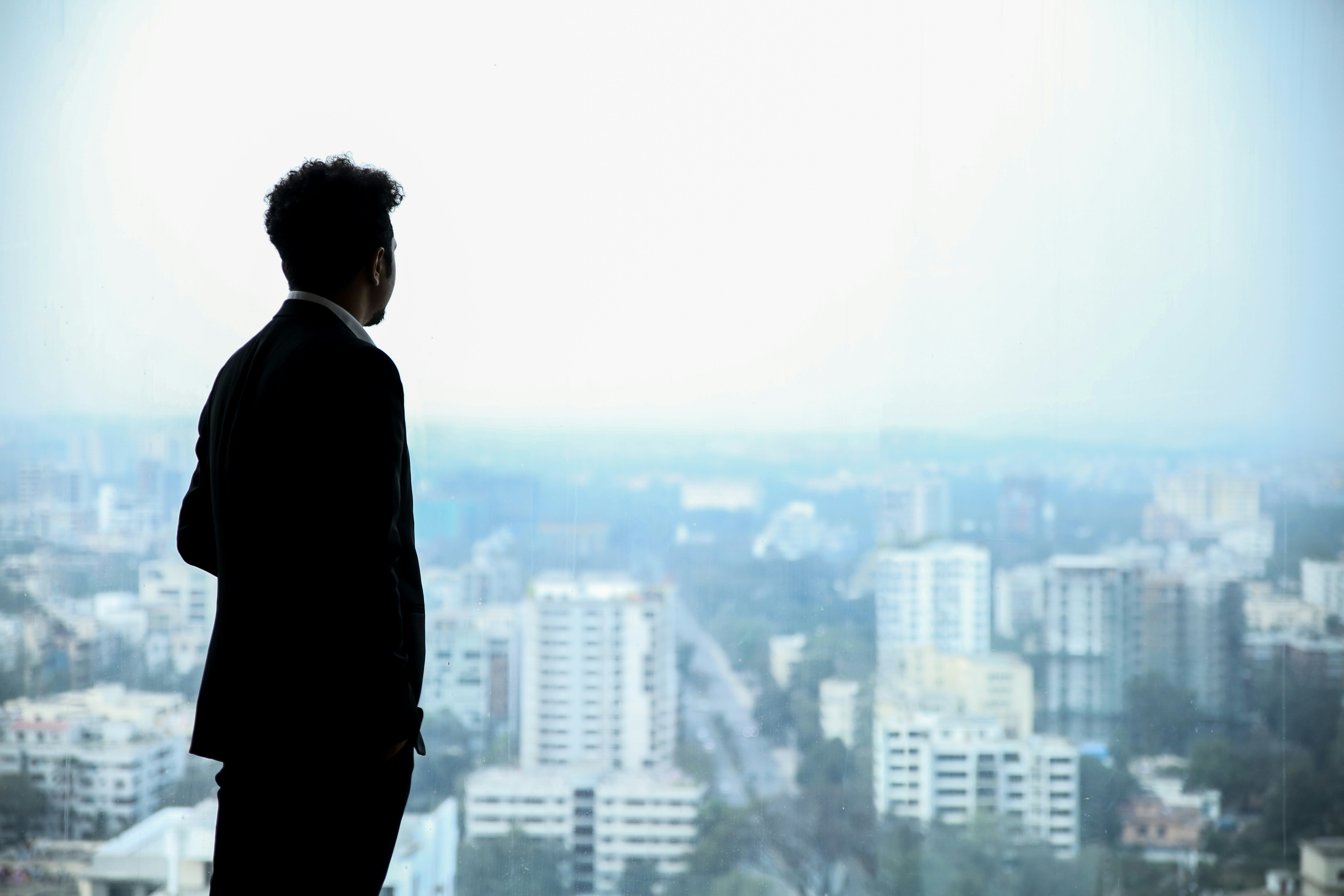 Man looking out window over city, symbolizing reflection and growth with OCD workbook support