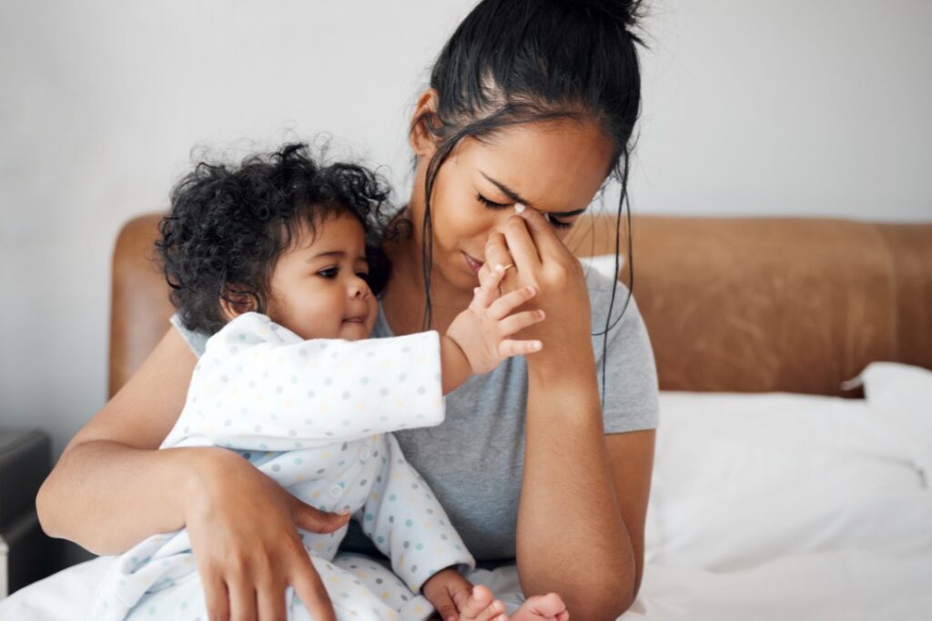 A woman carrying a child, and she looks so tired and is not feeling well.