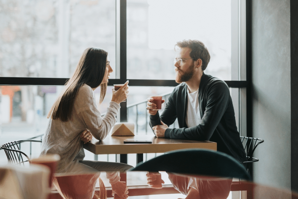 Two individual, having a cup of coffee outside, while actively listening with each other. 